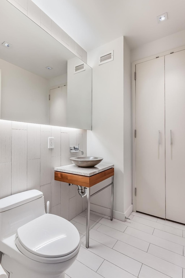 bathroom featuring toilet, a sink, and visible vents