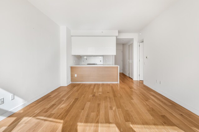 unfurnished living room featuring light wood finished floors and baseboards