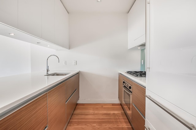 kitchen featuring light countertops, appliances with stainless steel finishes, white cabinets, a sink, and modern cabinets