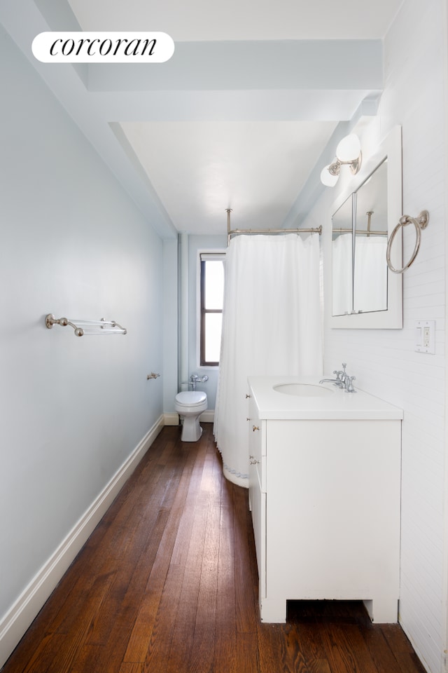 full bath featuring wood-type flooring, a shower with shower curtain, toilet, vanity, and baseboards