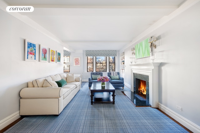 living area with built in shelves, a high end fireplace, visible vents, baseboards, and beam ceiling