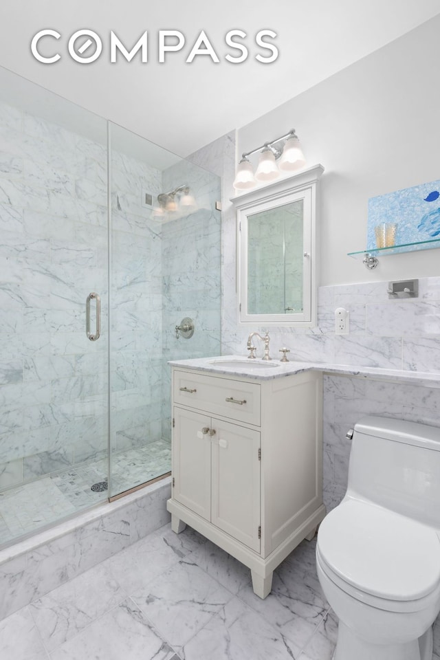 bathroom featuring a marble finish shower, toilet, marble finish floor, vanity, and tile walls