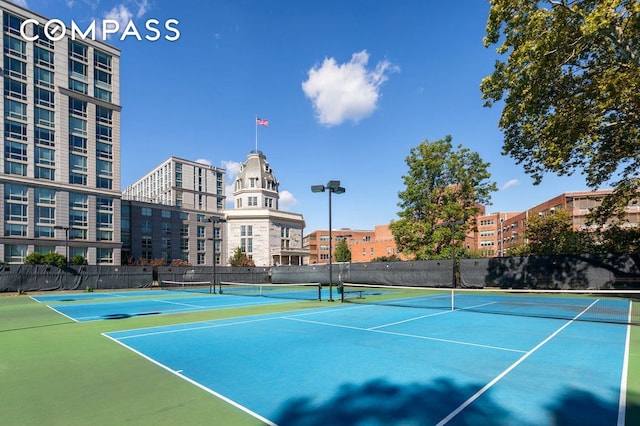 view of tennis court featuring a city view and fence