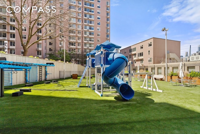 community play area featuring fence and a yard