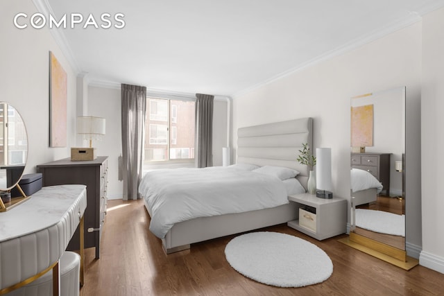 bedroom with ornamental molding, baseboards, and wood finished floors