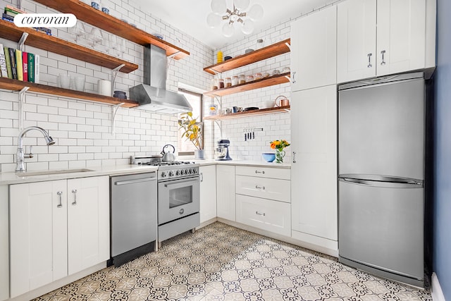 kitchen featuring open shelves, wall chimney exhaust hood, stainless steel appliances, and a sink