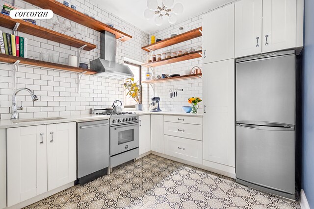 kitchen featuring stainless steel appliances, a sink, wall chimney exhaust hood, and open shelves