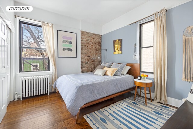 bedroom with wood finished floors, visible vents, and radiator