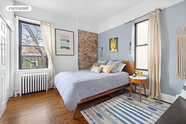 bedroom featuring visible vents, radiator heating unit, and wood finished floors