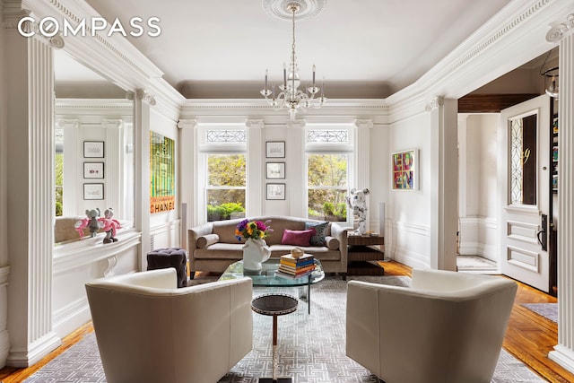 living area with a decorative wall, wainscoting, crown molding, and an inviting chandelier