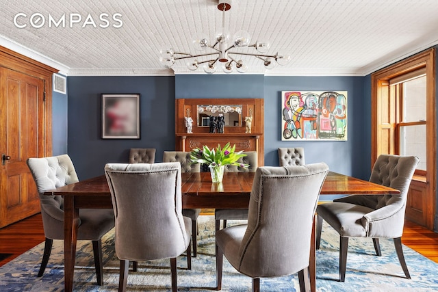 dining space with crown molding, wood finished floors, visible vents, rail lighting, and an inviting chandelier