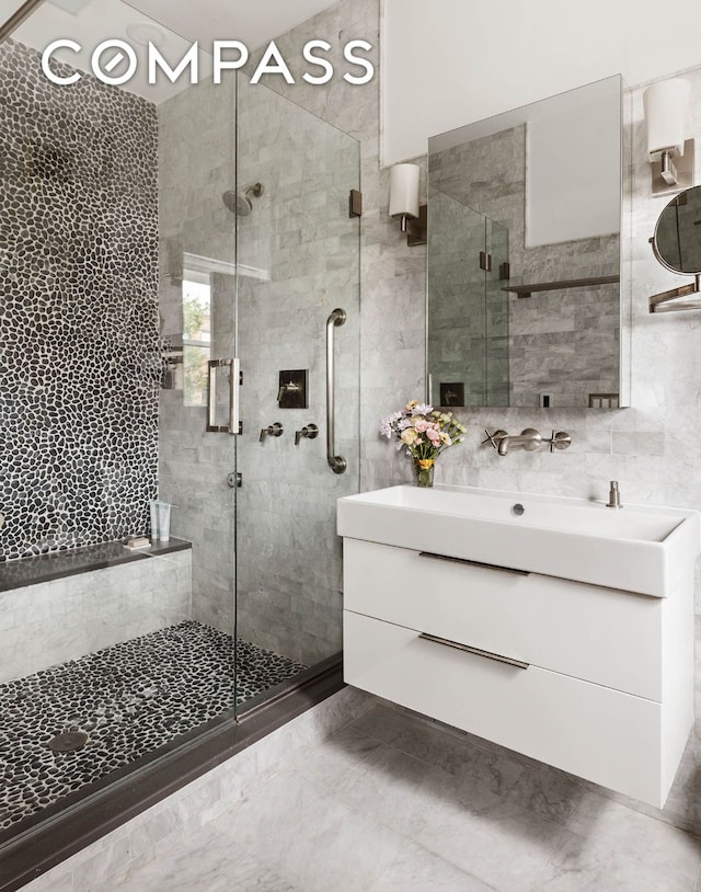 full bathroom with a stall shower, backsplash, tile walls, and vanity