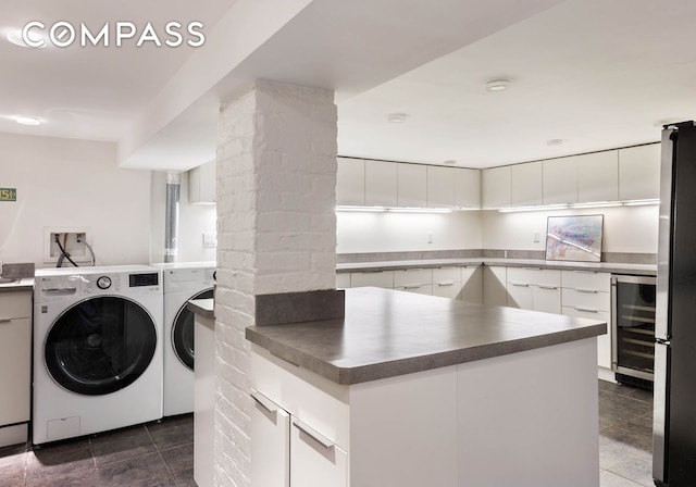 washroom featuring laundry area, beverage cooler, washer and dryer, and dark tile patterned floors