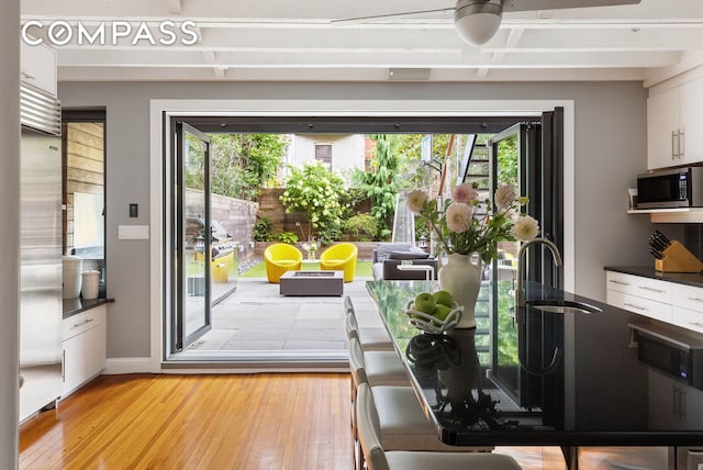 doorway to outside with a sink, light wood-style flooring, and baseboards