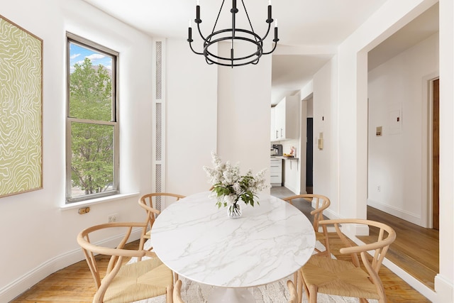 dining space featuring plenty of natural light, baseboards, light wood-style flooring, and a notable chandelier