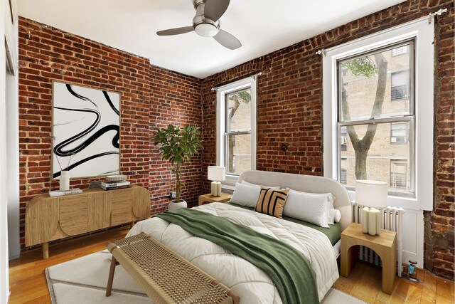 626 E 14th St Unit 11/12, New York City, NY 10009 - bedroom with brick wall, radiator heating unit, light wood-type flooring, and a ceiling fan