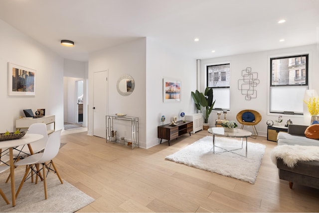 living area with baseboards, light wood-type flooring, and recessed lighting