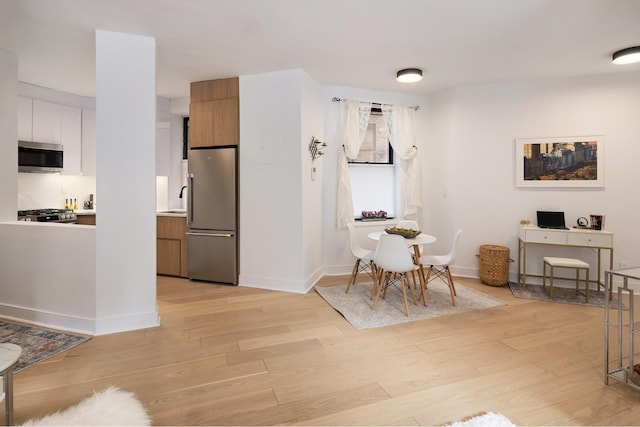 dining area featuring light wood-style flooring and baseboards