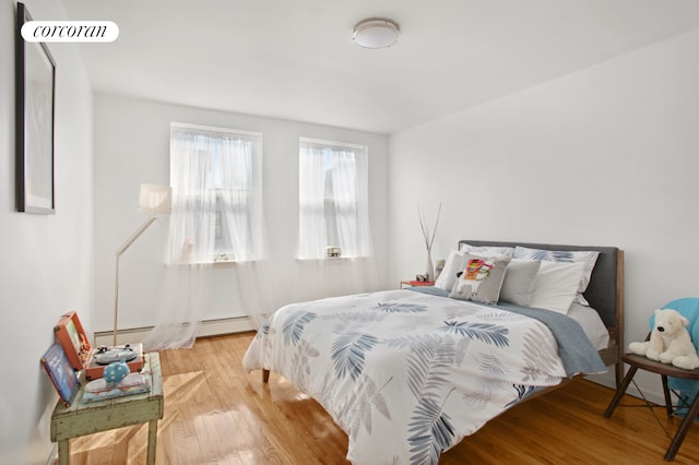 bedroom featuring a baseboard radiator, wood-type flooring, and visible vents