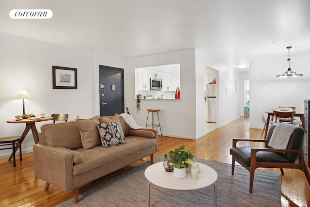 living area featuring a chandelier, baseboards, visible vents, and light wood-style floors