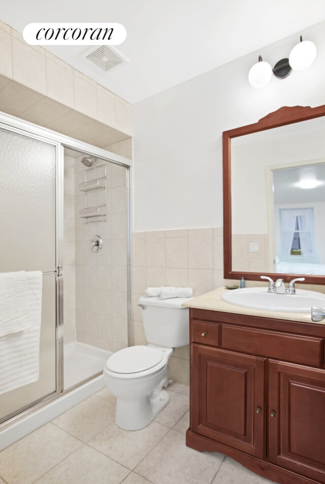 full bath featuring tile patterned flooring, a shower stall, visible vents, and tile walls