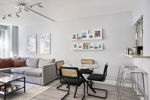 living room featuring wood finished floors, rail lighting, and baseboards