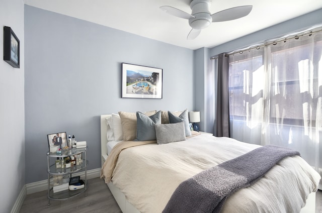 bedroom featuring baseboards, wood finished floors, and a ceiling fan