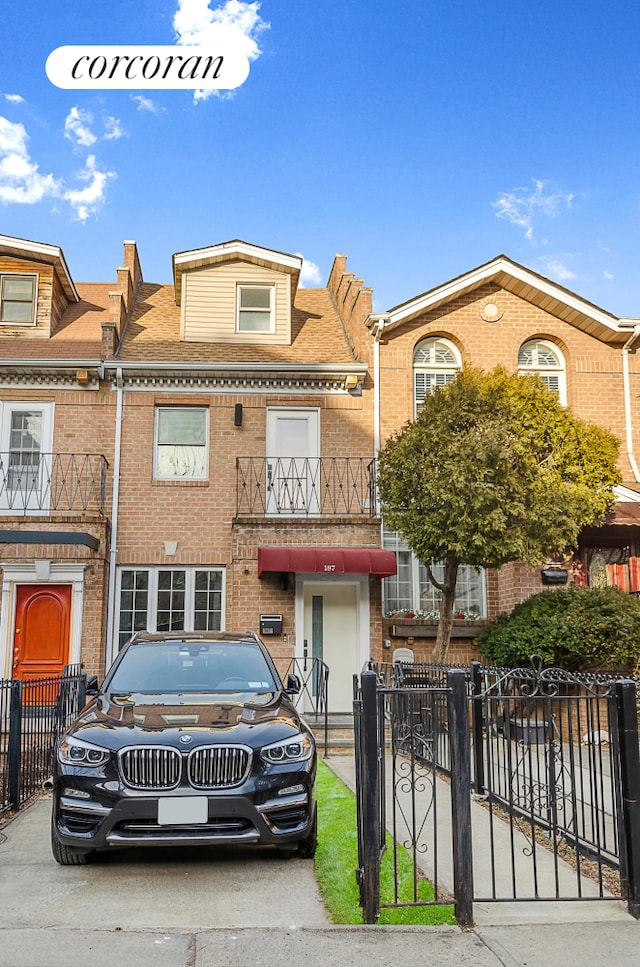 view of front of property featuring a fenced front yard, brick siding, and a balcony