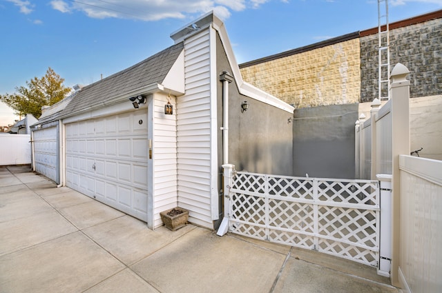 garage featuring concrete driveway and fence