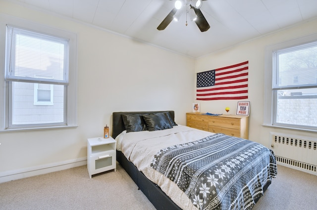 carpeted bedroom with radiator heating unit, ornamental molding, ceiling fan, and baseboards