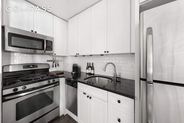 kitchen with appliances with stainless steel finishes, backsplash, a sink, and white cabinetry