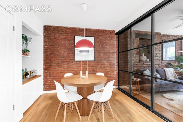 118 Suffolk St Unit 3A, New York City, NY 10002 - dining space with light wood-style floors, brick wall, and baseboards