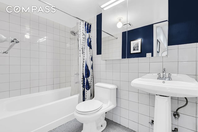 bathroom featuring toilet, visible vents, tile walls, tile patterned floors, and shower / bathtub combination with curtain