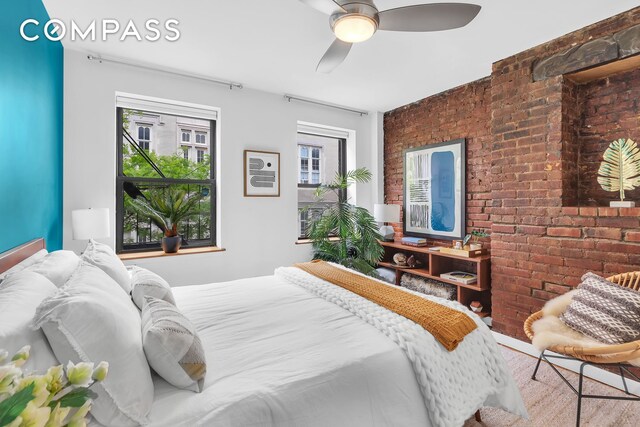 bedroom featuring a ceiling fan and brick wall