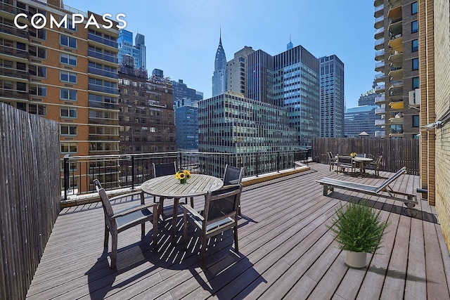 wooden terrace with a view of city and outdoor dining space