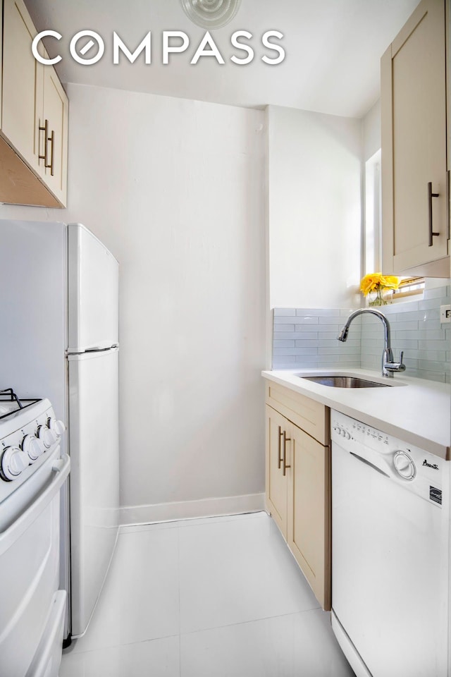 kitchen with backsplash, baseboards, light countertops, white appliances, and a sink