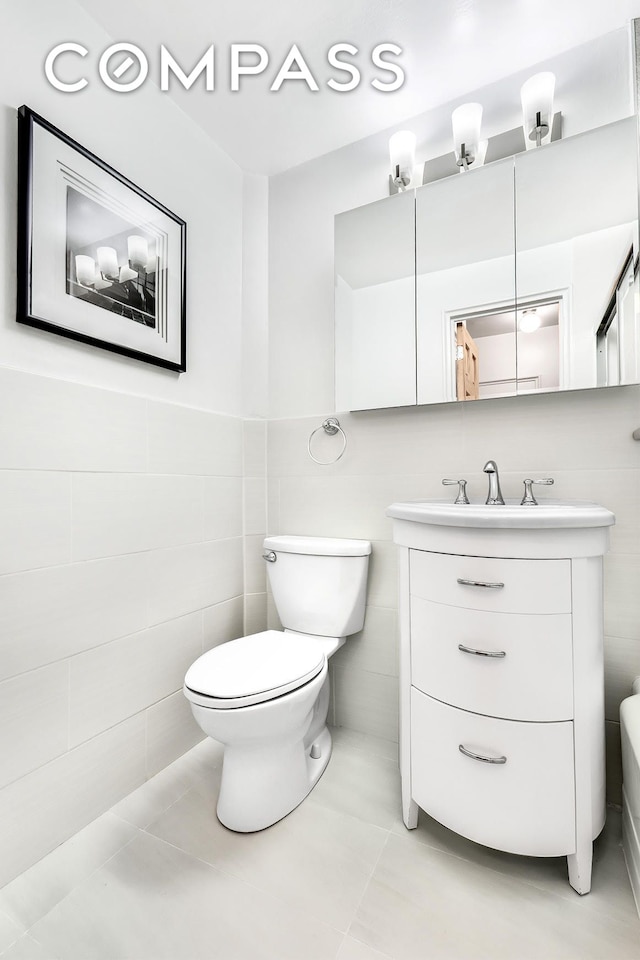 bathroom featuring vanity, tile walls, toilet, and tile patterned flooring