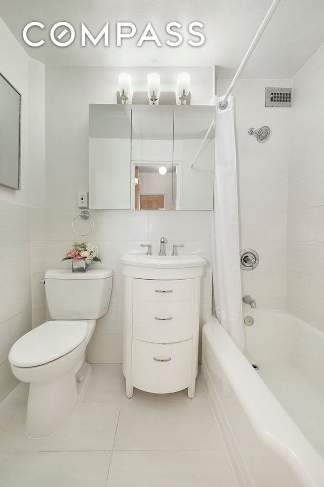 full bath with tile patterned floors, shower / bath combo with shower curtain, toilet, tile walls, and vanity