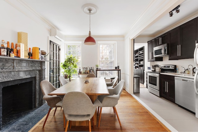 dining room with light wood finished floors, a premium fireplace, and ornamental molding