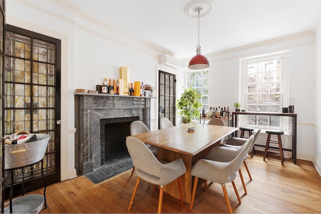 dining area with a wall unit AC, wood finished floors, a high end fireplace, and crown molding