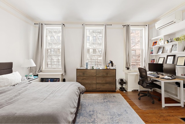 bedroom with a wall unit AC and wood finished floors