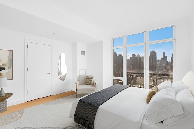 bedroom featuring visible vents, a view of city, baseboards, and wood finished floors