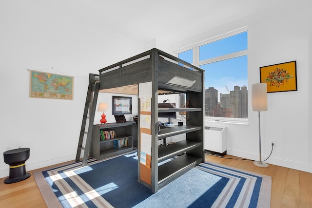 bedroom featuring a view of city, wood finished floors, and baseboards