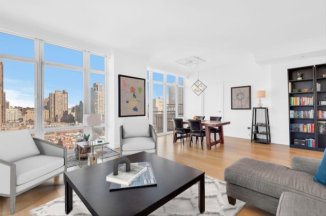 living area with light wood-style flooring, a view of city, and floor to ceiling windows