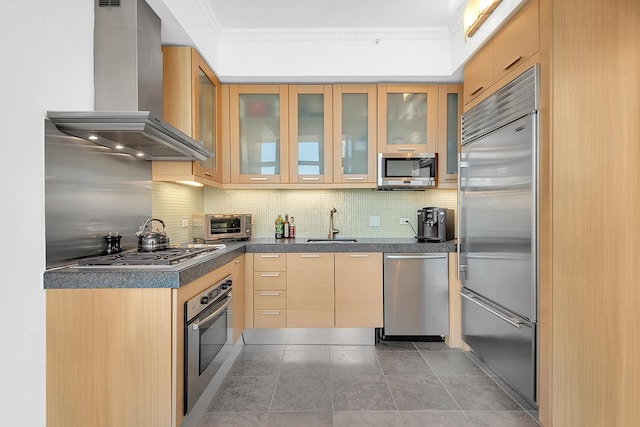 kitchen featuring ornamental molding, decorative backsplash, stainless steel appliances, dark countertops, and wall chimney range hood