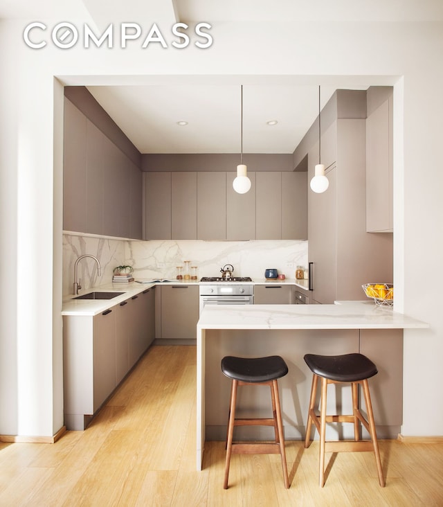 kitchen featuring gray cabinetry, modern cabinets, a peninsula, and a sink