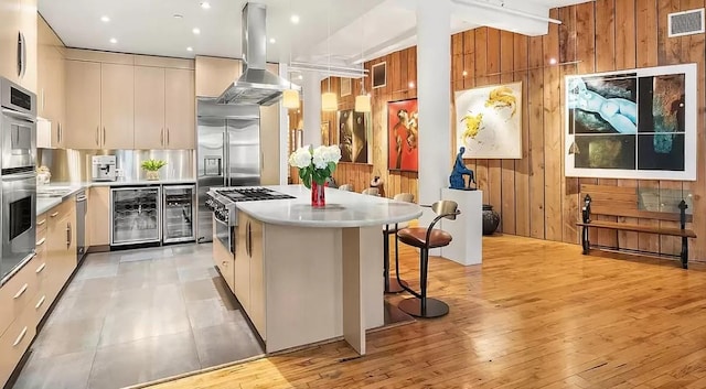 kitchen with modern cabinets, wine cooler, visible vents, and island range hood