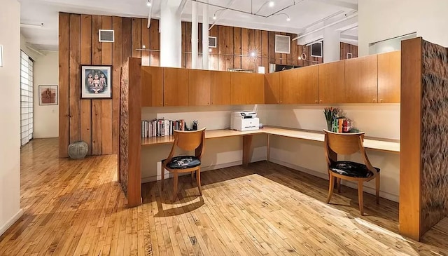 office space with light wood-type flooring, built in desk, and visible vents
