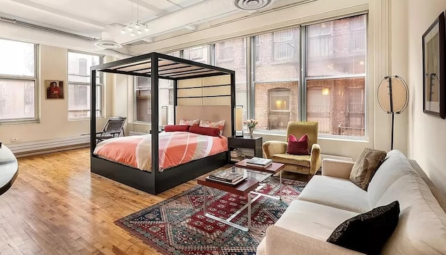 bedroom featuring a baseboard radiator, a chandelier, and wood finished floors
