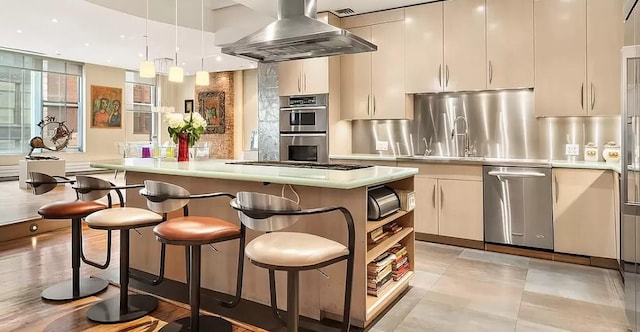 kitchen featuring island exhaust hood, a breakfast bar, light countertops, a kitchen island, and appliances with stainless steel finishes